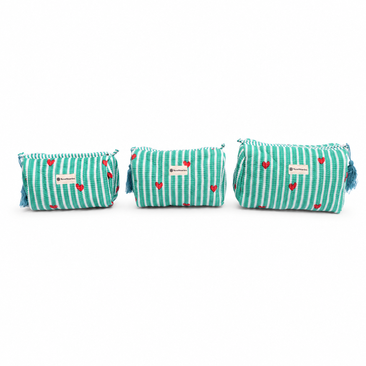 Three small cylindrical cosmetic pouches with a mint green and white striped pattern, accented with small red hearts and blue tassels, displayed on a white background.