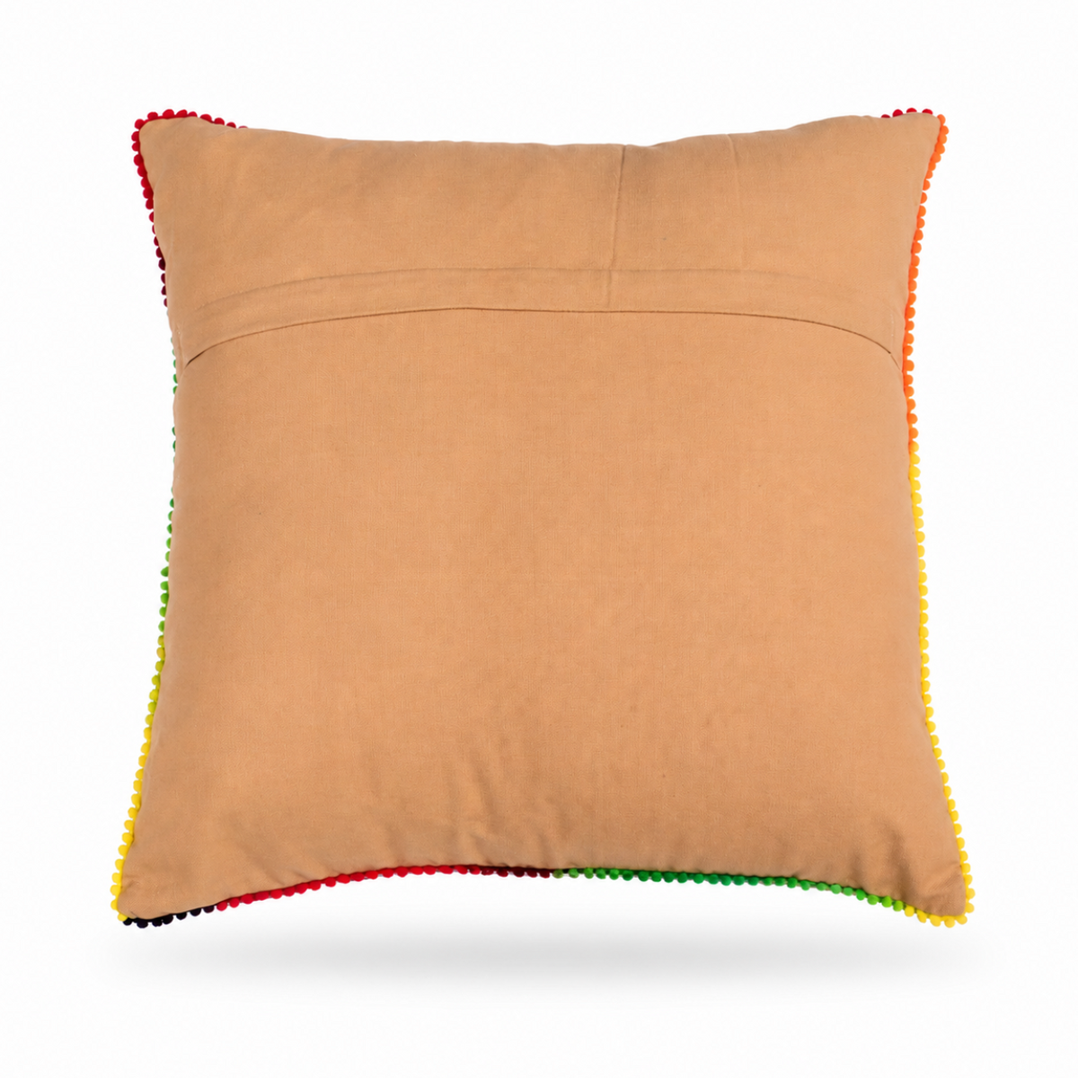 The backside of a square tan throw pillow featuring a vibrant, colorful hand-stitched floral pattern in the center, finished with multicolored pom-pom trim along the edges, shown against a plain white background.