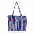 A navy blue and white vertically striped tote bag with small red hearts scattered across the front, featuring two shoulder straps and a small white brand label on the upper right side.