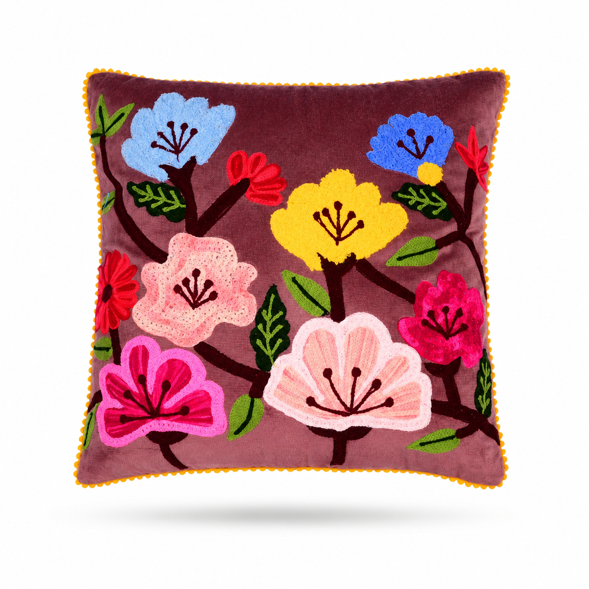A square throw pillow with a deep plum purple velvet background, featuring colorful embroidered flowers in pink, yellow, blue, and red with green leaves, finished with a yellow pom-pom trim.