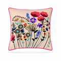 A square decorative throw pillow with a vibrant floral embroidery design on a light beige background, finished with a bright pink pom-pom trim, shown against a plain white background.