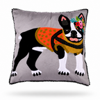 A square gray throw pillow with black pom-pom trim, featuring a stylized embroidered PUG dog wearing an orange patterned sweater and a colorful floral headband, set against a plain white background.
