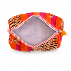 An open quilted cosmetic pouch with a vibrant orange, pink, and tiger-print pattern, featuring a striped zipper and a small orange tassel, shown on a white background.