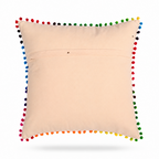 back of a square beige throw pillow featuring a colorful embroidered toucan holding a bouquet of flowers, finished with a border of multicolored pom-poms, shown on a white background.