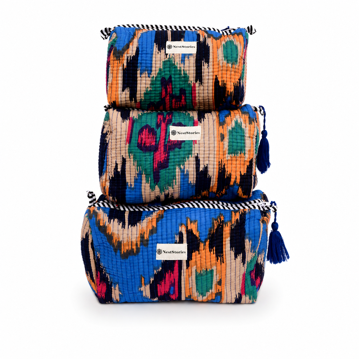 Three stacked rectangular zip pouches with colorful ikat-style patterns in blue, orange, pink, green, and black, each with a tassel zipper pull and a visible SmallWaves brand label, on a white background.