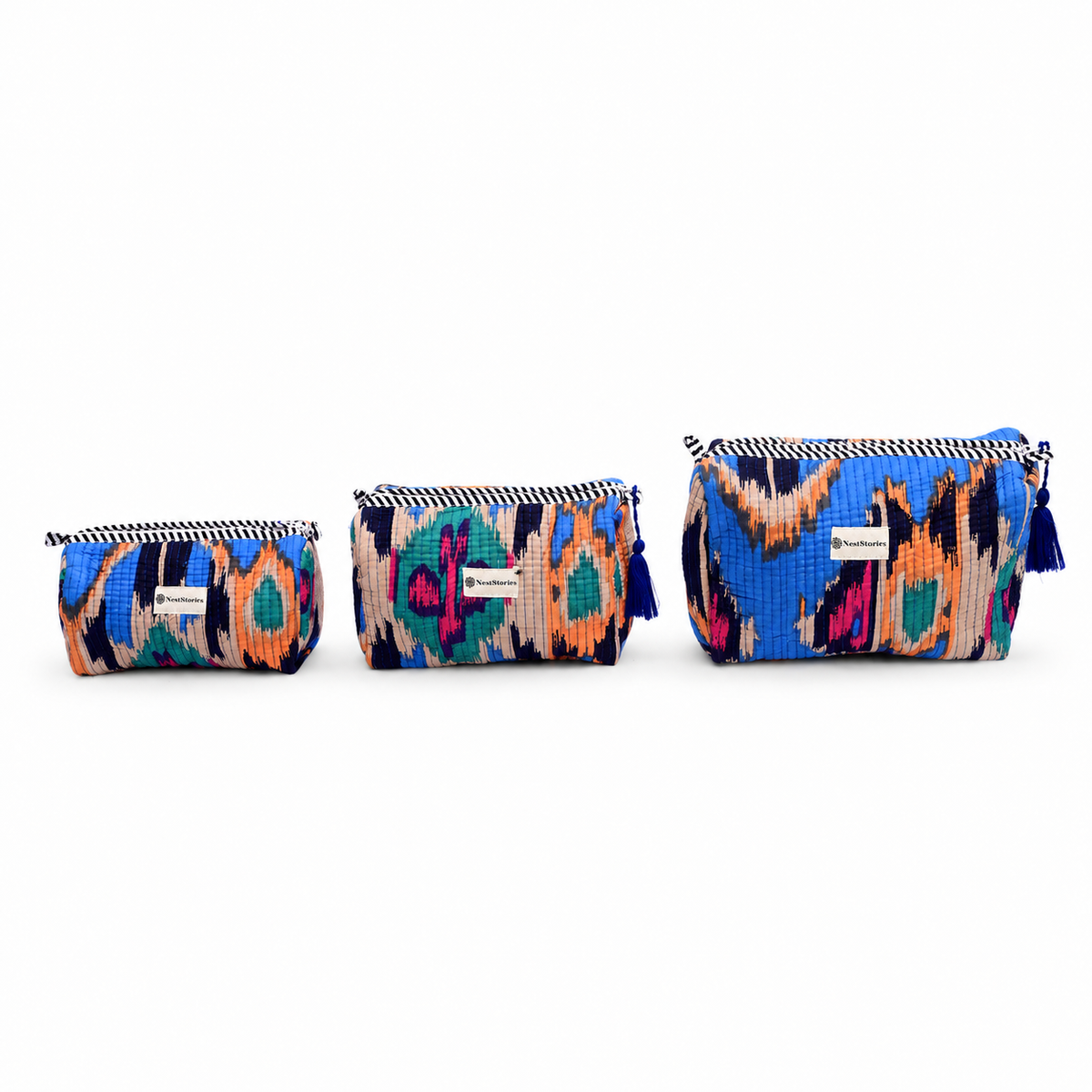 Three small zip pouches in a matching multicolor ikat pattern, arranged by size on a plain white background. Each pouch has a black and white striped zipper, a blue tassel zipper pull, and a small white brand label.