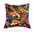 A square decorative throw pillow featuring a vibrant, multicolored floral embroidery pattern on an olive green velvet-like fabric, finished with colorful pom-pom trim along the edges.