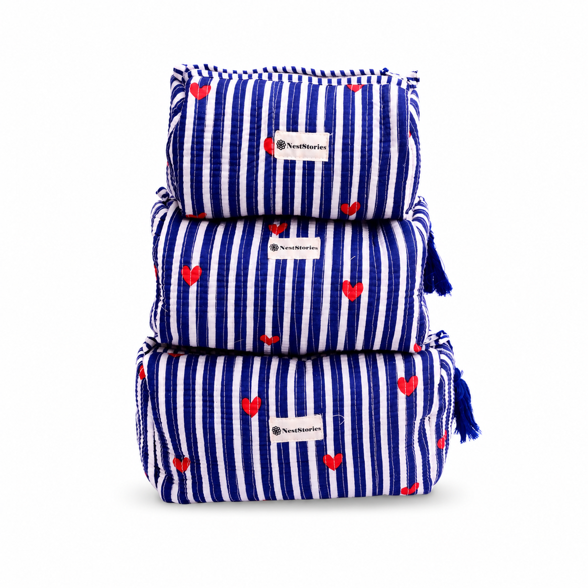 Three stacked reusable cloth pouches with a blue and white vertical stripe pattern and small red heart prints. Each pouch has a white fabric label with the brand name 'NewMeasures' and a blue tassel on the side.
