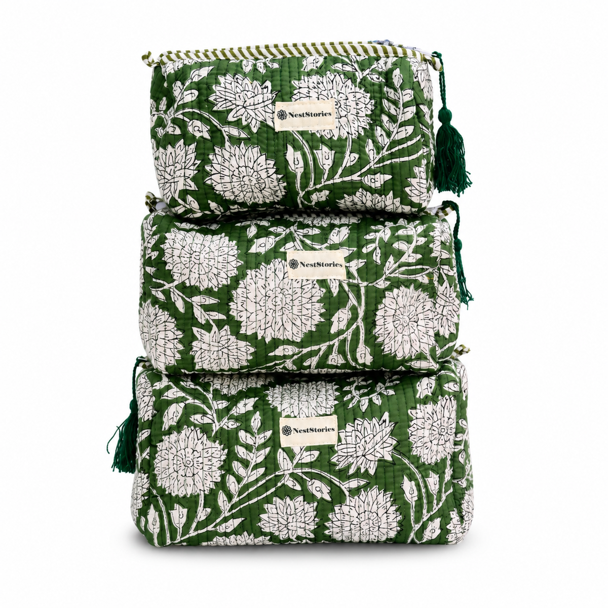 Three stacked quilted cosmetic pouches in green and white floral print with tassel zipper pulls, shown on a white background.