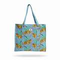 A woven tote bag with a turquoise and purple patterned background, decorated with golden-yellow leopards, featuring two top handles and a small white brand patch on the front.