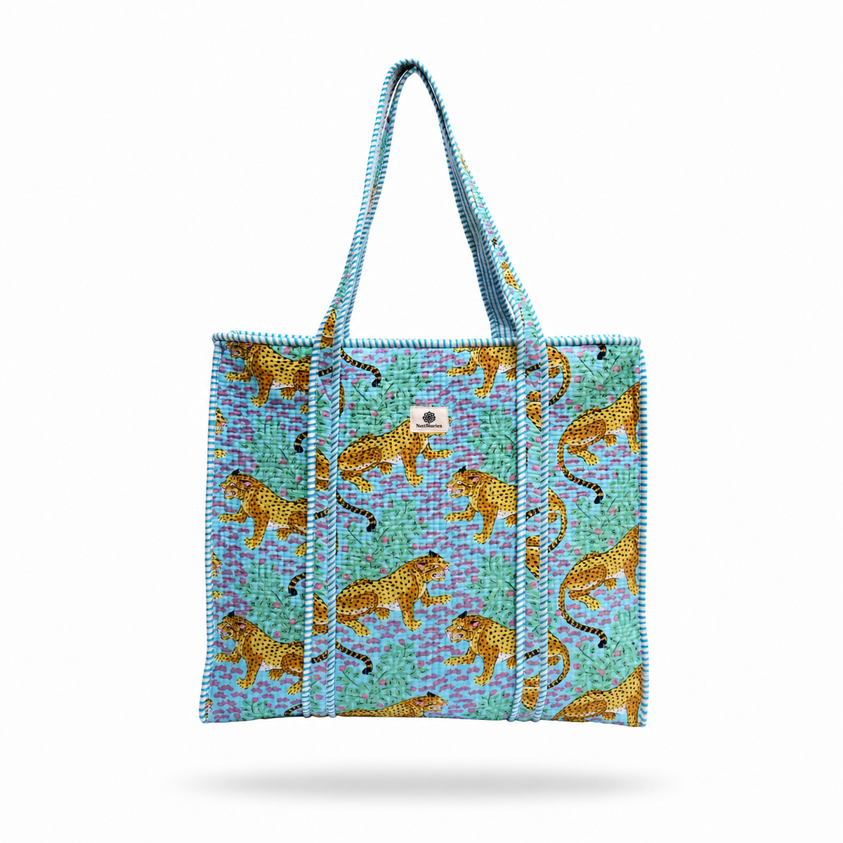 A woven tote bag with a turquoise and purple patterned background, decorated with golden-yellow leopards, featuring two top handles and a small white brand patch on the front.