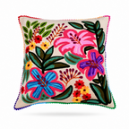 A square decorative throw pillow with a colorful embroidered floral pattern on a cream background, finished with a multicolor pom-pom trim, shown on a off white background.